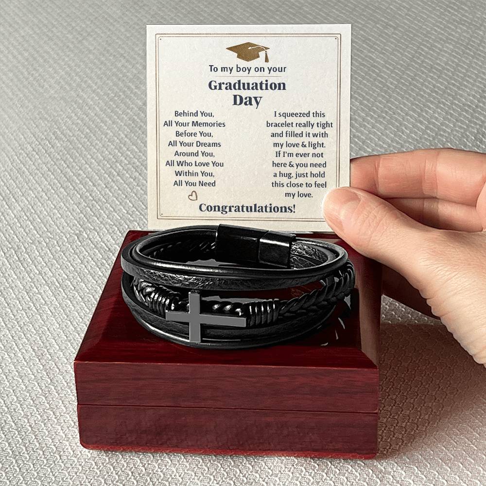 To My Boy Graduation Day card beside a men's cross bracelet graduation gift on a wooden box.