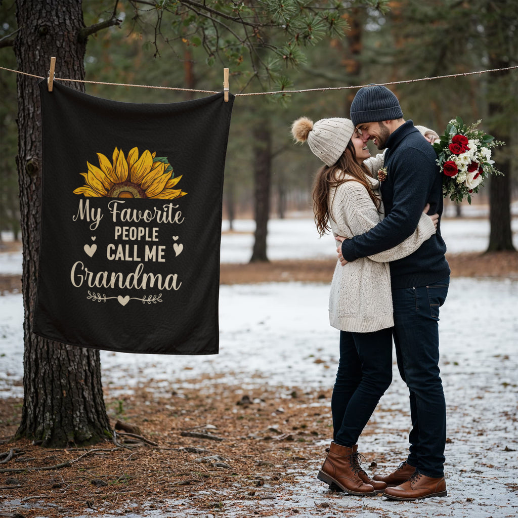 My Favorite People Call Me Grandma Coral Fleece Blanket hanging near a couple in a snowy forest setting.