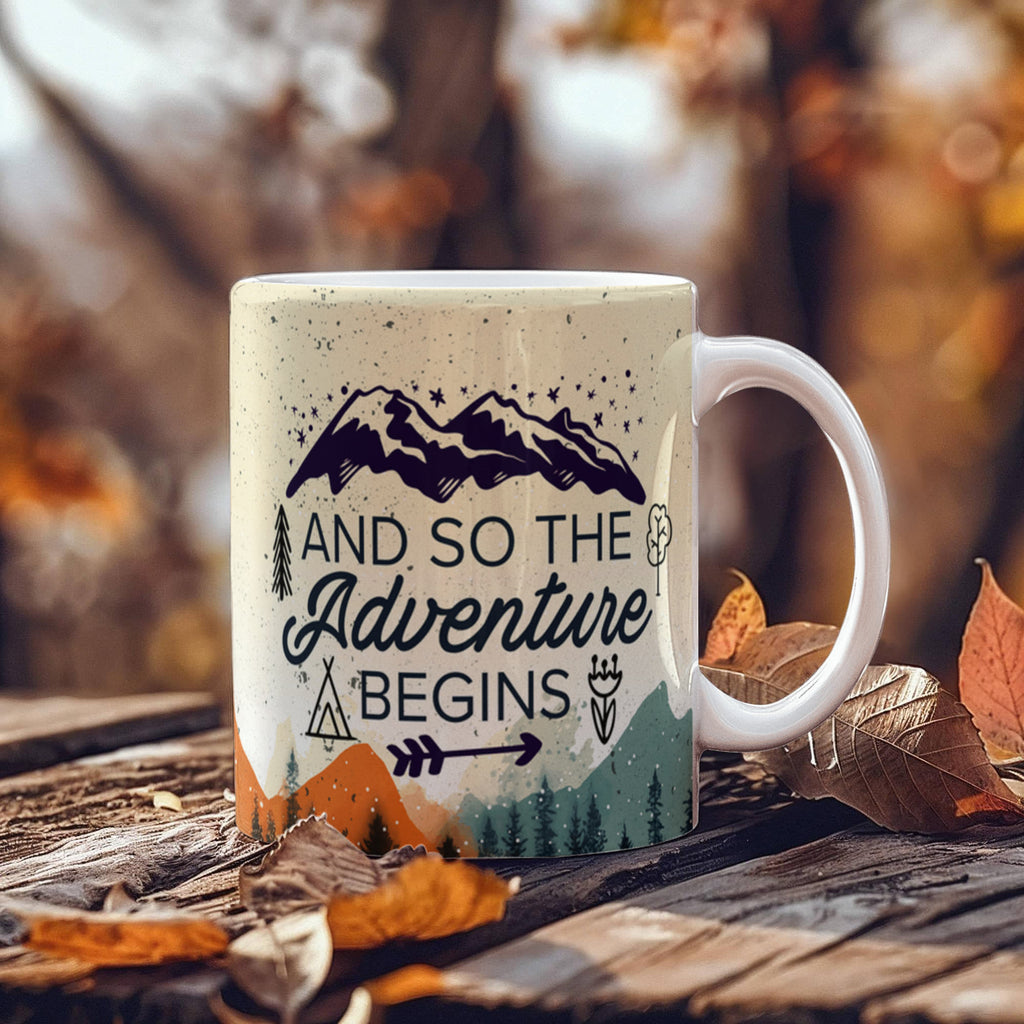custom ceramic coffee mug with mountain design and text 'And so the Adventure begins' on a wooden surface.